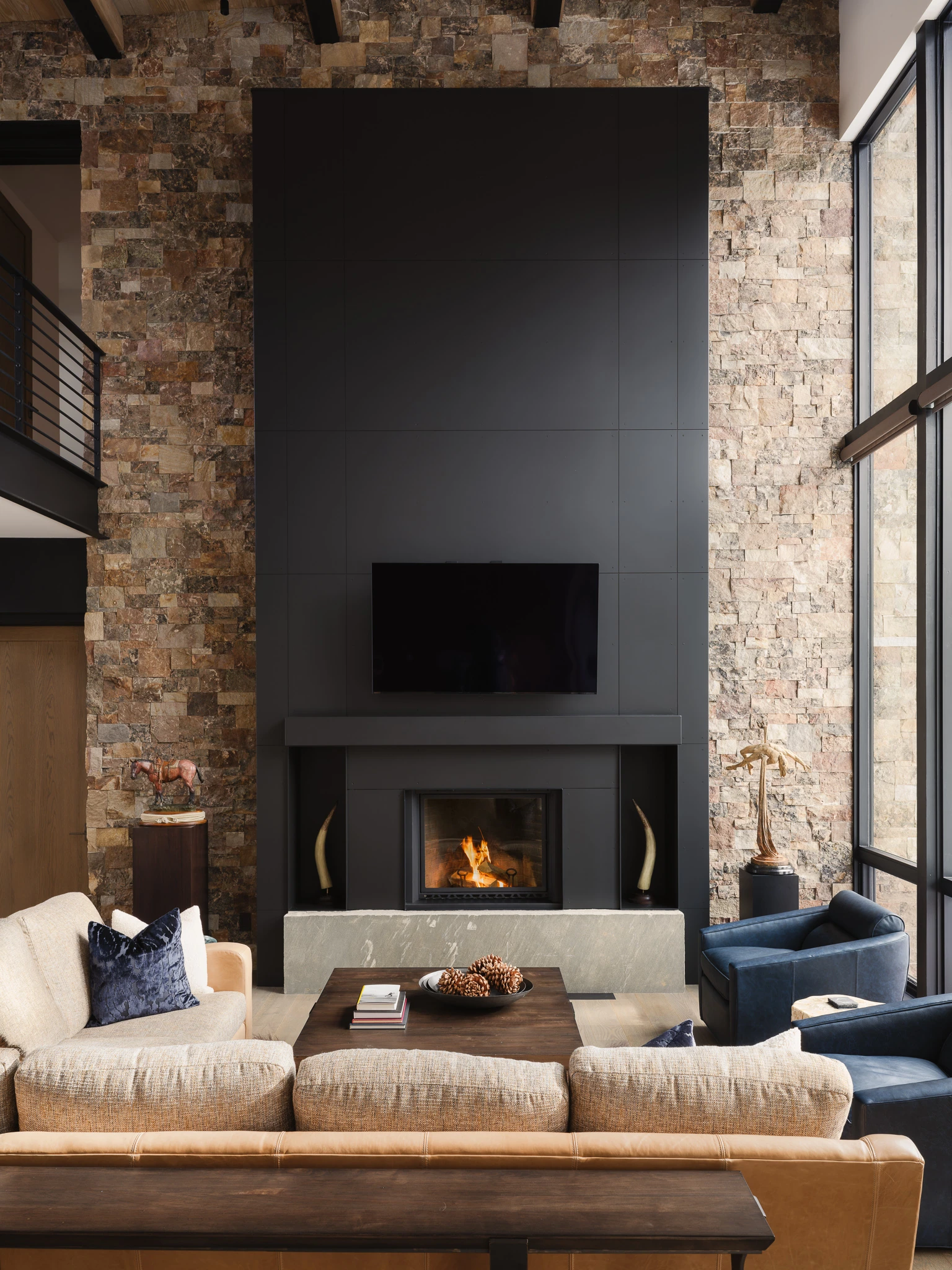 Great room fireplace and television wall with stacked-stone surround — interior design photography Big Sky Montana, Speedwell Cabin